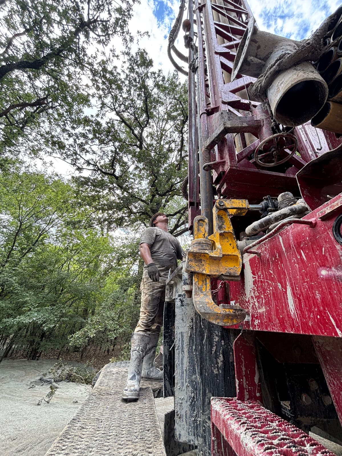 Triangle J driller guiding drill pipe on the rig at a wooded residential home site