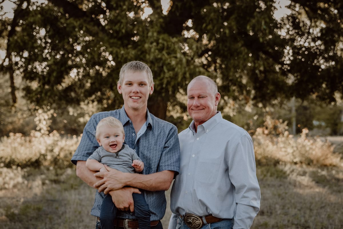 Three generations of the Gandy family, founders of Triangle J Water Wells, standing together under an oak tree