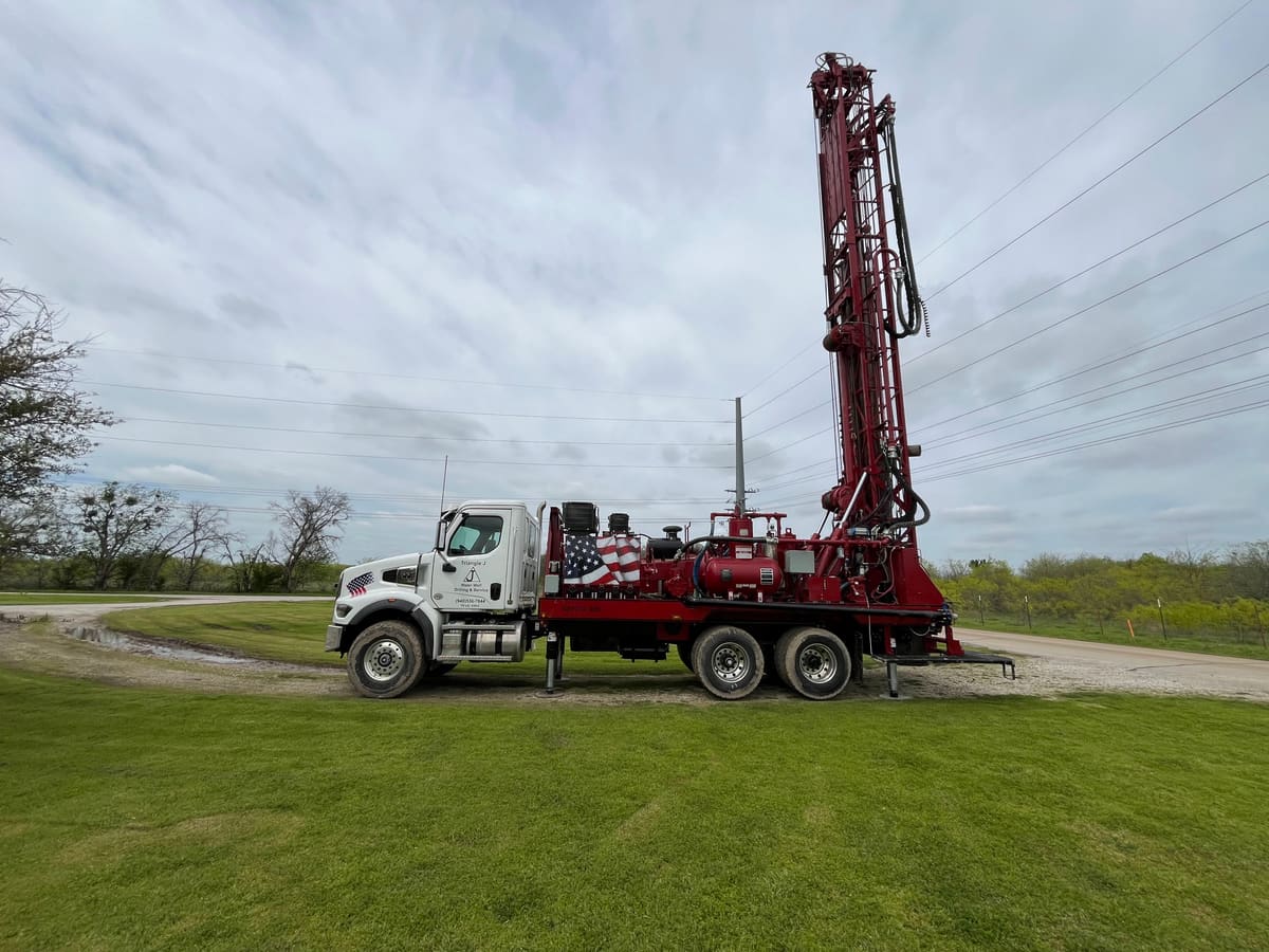 Triangle J drilling rig truck with mast raised at a North Texas job site